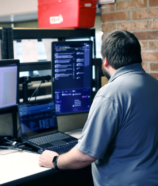 D-best team member standing in front of computers helping provide IT Support in Fort Smith