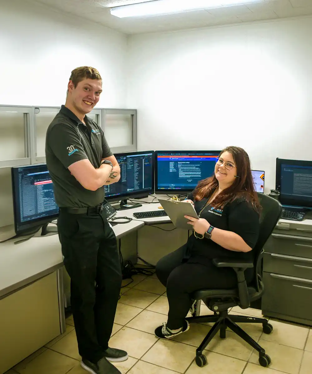 Two D-best employees standing next to computers in the office helping provide IT support in Fort Smith
